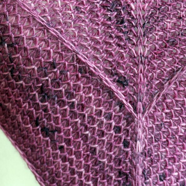 A close up on the spine and border of a cowlette knit in purple yarn with two brioche patterns and two slipped stitch bands