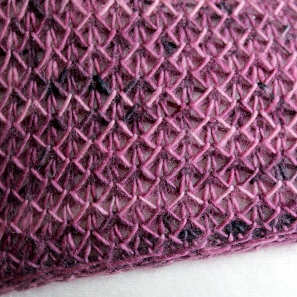 A close up on the border of a cowlette knit in purple yarn with a brioche pattern and a slipped stitch band
