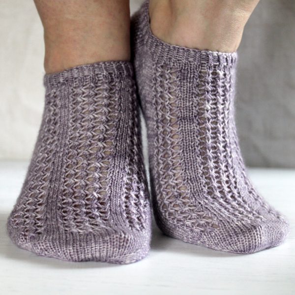 A pair of modelled socks with three panels of lace on the foot, knit in purple yarn