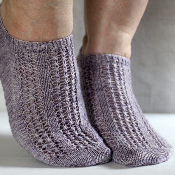 A pair of modelled socks with three panels of lace on the foot, knit in purple yarn