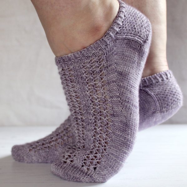 A pair of modelled socks with three panels of lace on the foot, knit in purple yarn