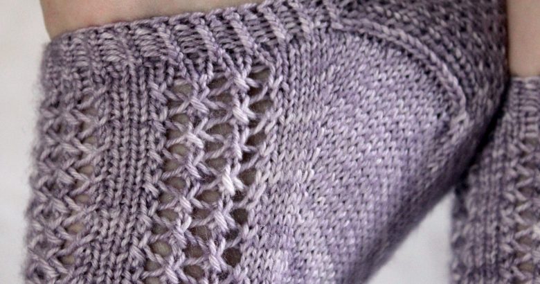 A close up on the heel and cuff of modelled socks with three panels of lace on the foot, knit in purple yarn