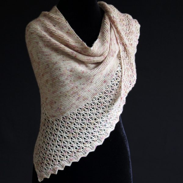 A shawl with an arrow shaped lace border and garter stitch body of a shawl knit in pale yellow speckled yarn and draped around a mannequin