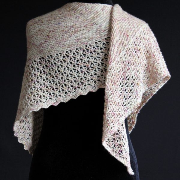 A shawl with an arrow shaped lace border and garter stitch body of a shawl knit in pale yellow speckled yarn and draped around a mannequin