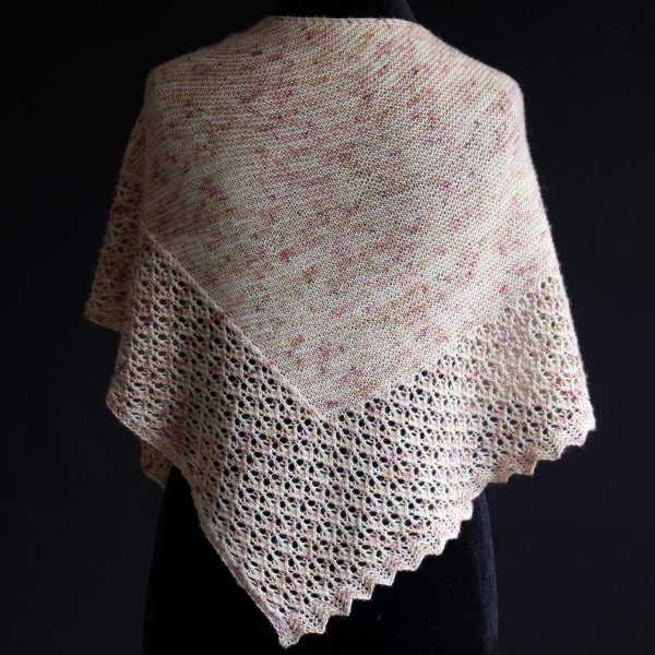 A shawl with an arrow shaped lace border and garter stitch body of a shawl knit in pale yellow speckled yarn and draped around a mannequin