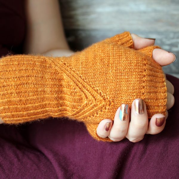 Fingerless mitts in orange yarn with a twisted rib pattern that decreases to a point below the ring finger.