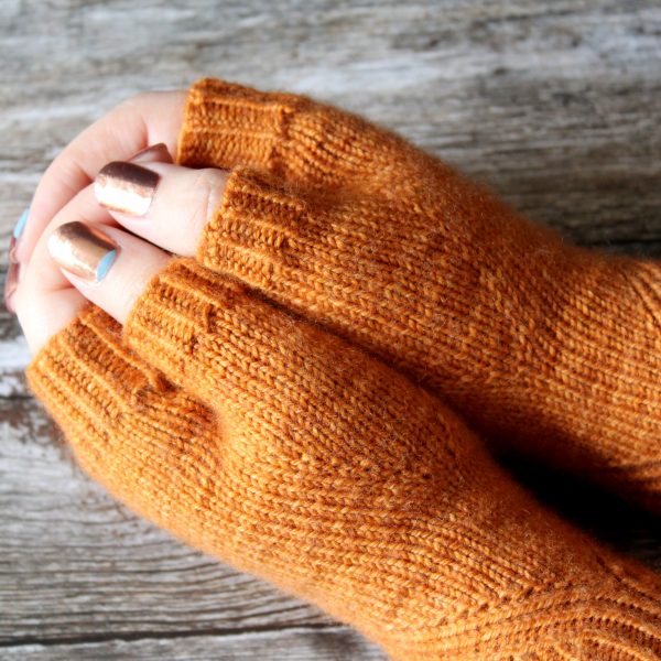 The thumbs of fingerless mitts in orange yarn with a twisted rib pattern.