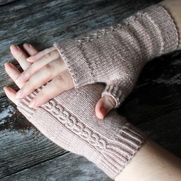 A pair of fingerless mitts with a twisted cable pattern, knit in a pale tan yarn