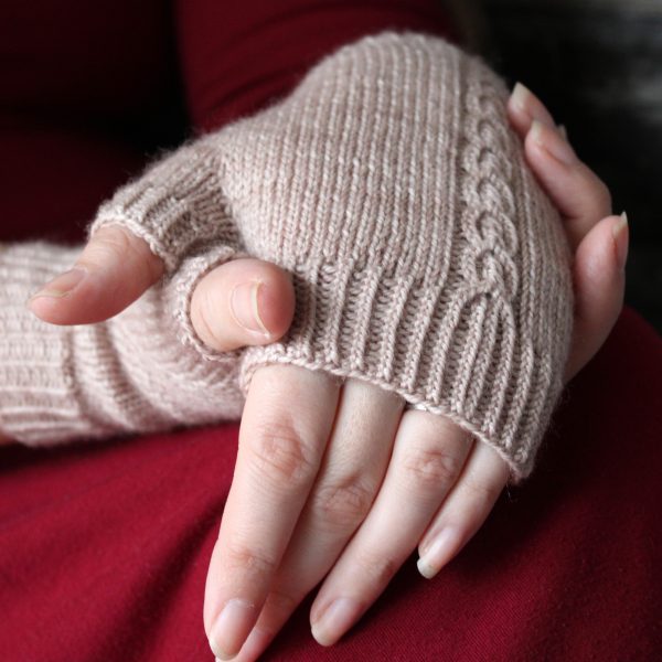 A pair of fingerless mitts with a twisted cable pattern, knit in a pale tan yarn