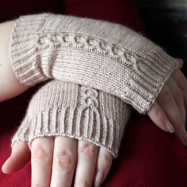 A pair of fingerless mitts with a twisted cable pattern, knit in a pale tan yarn